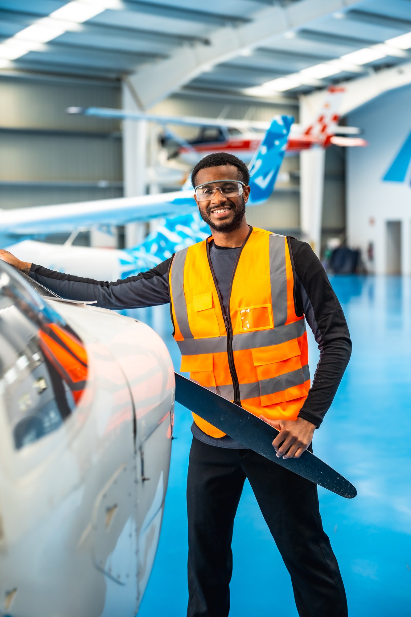 smiling-engineer-with-aircraft-propeller-in-hangar-2026-01-09-10-54-42-utc