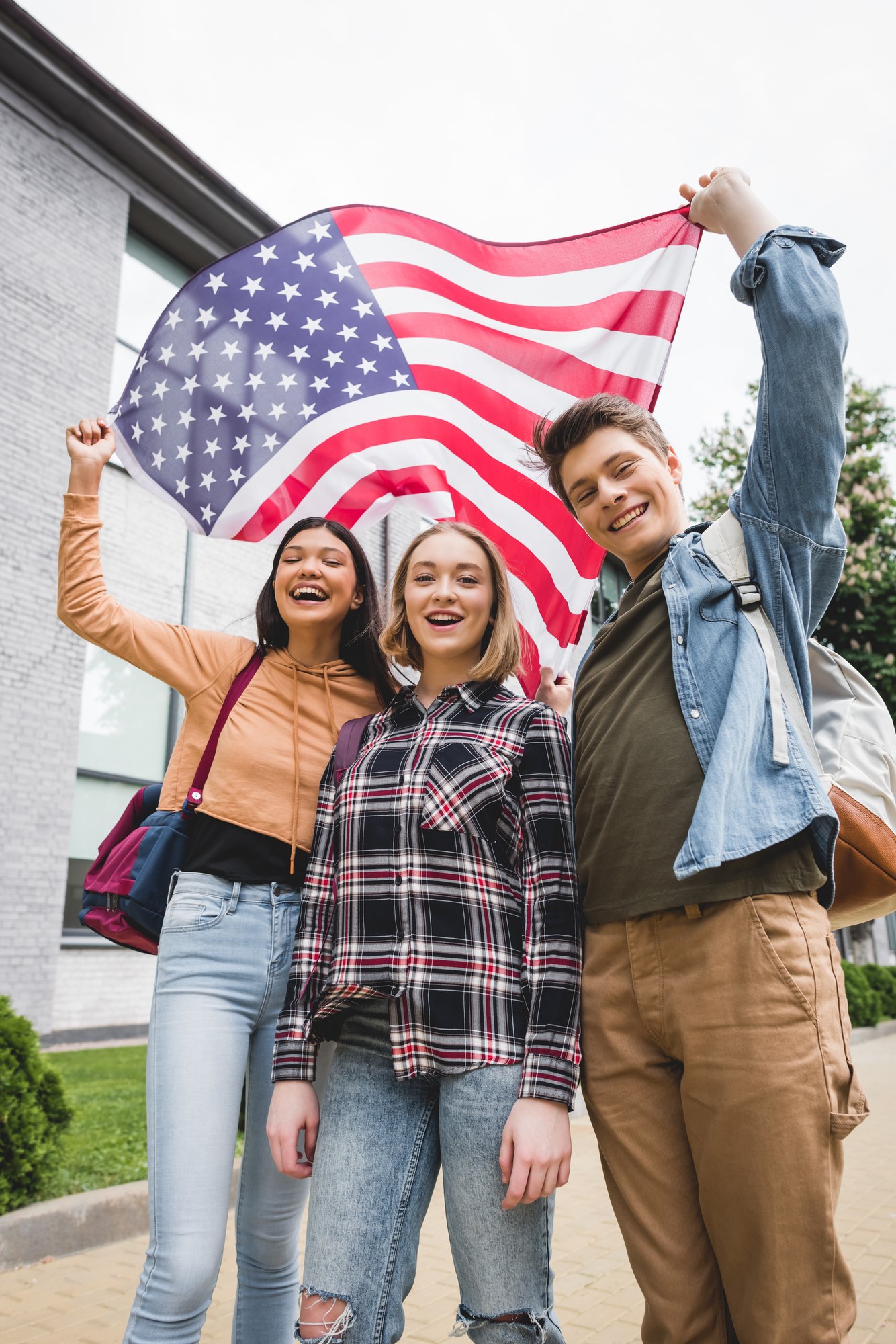 smiling-friends-holding-american-flag-outside-buil-2026-01-06-00-09-36-utc